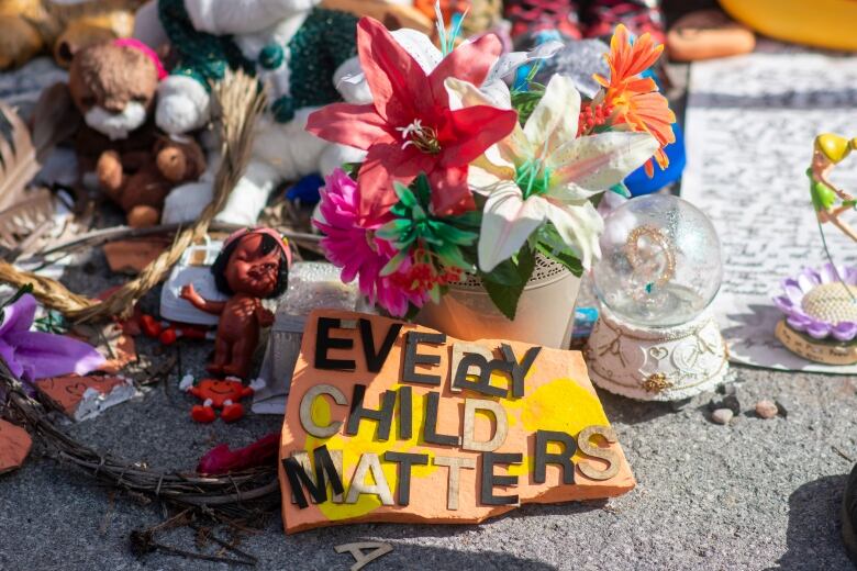 A close-up image of a snow globe and several small figurines next to a sign that reads 