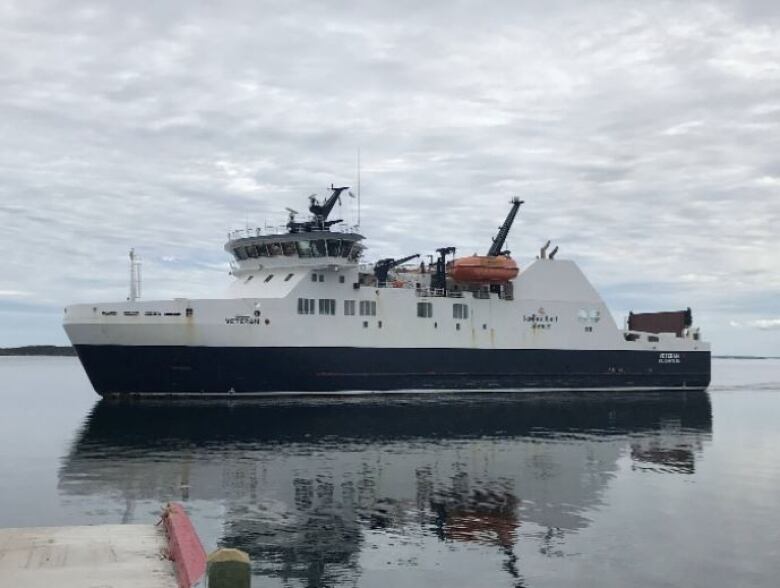 A large ferry floats on the ocean on a cloudy day.