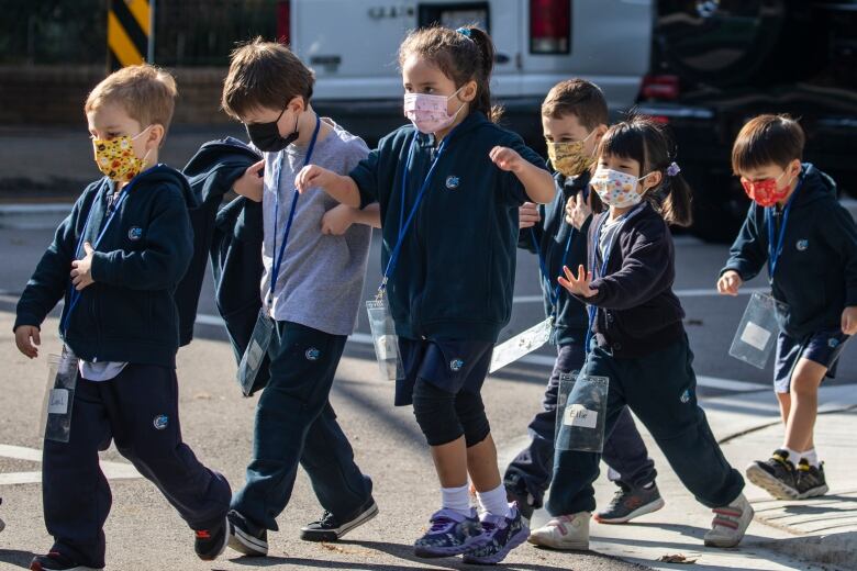 A group of masked children in a line.