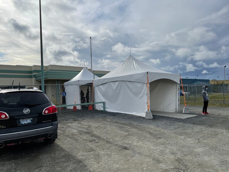 A white tent stands before a building. 