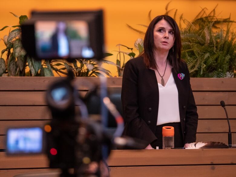 A woman stands at a desk.