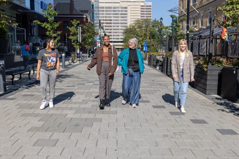 Four women walking down a cobblestone lane