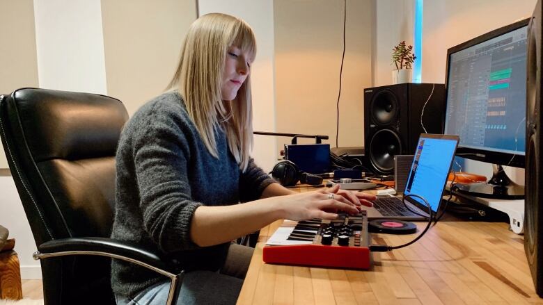 A white women with blonde hair in an at-home music studio