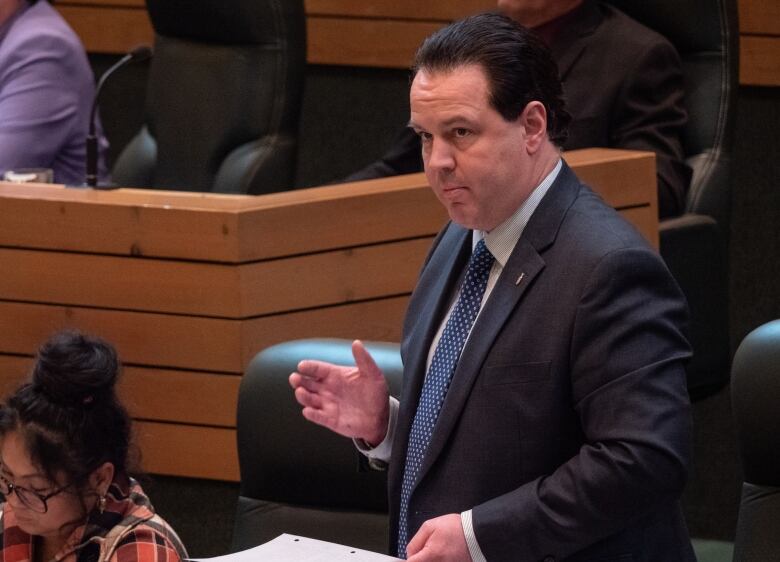 A man stands speaking in a territorial legislature.