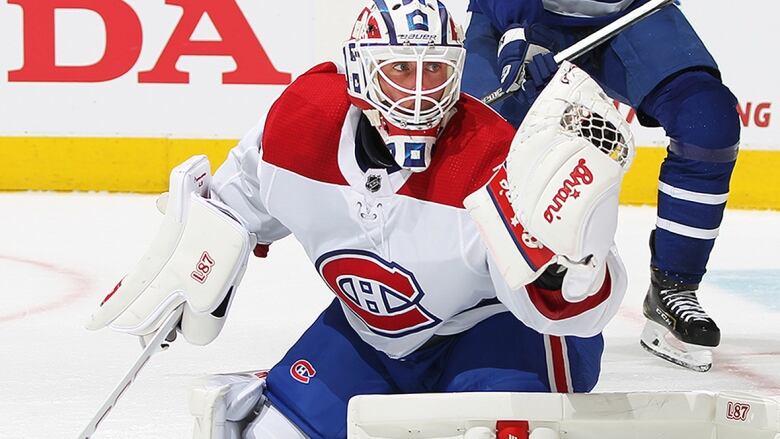 Hockey goalie lunges to stop a puck.