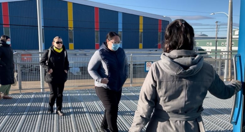 Three women wearing black jackets entering a courthouse