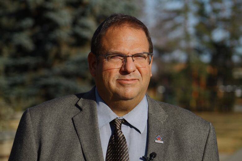 A man with glasses and a grey suit. 