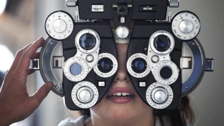 A patient sits for an eye exam at an optometrist's office.