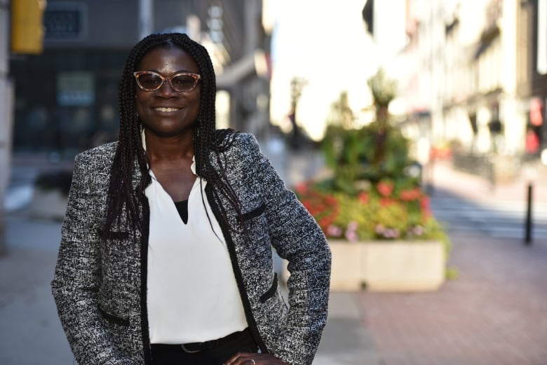 A woman in a white shirt and grey blazer smiles at the camera.