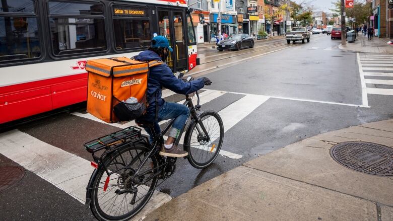 A person on a bike next to a streetcar, they are not in a bike lane.