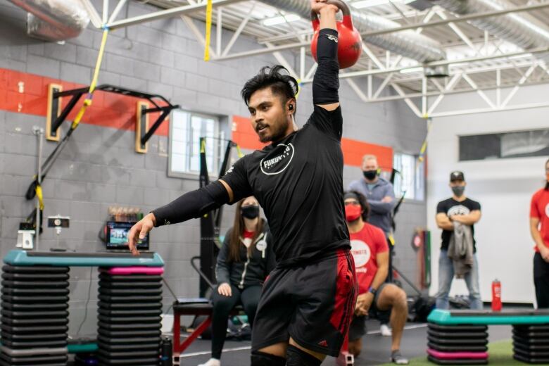 Man in a gym lifting a weight over his head.