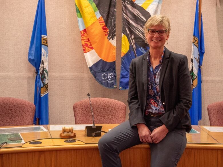 Mayor Laura Cabott sits on a table at city council.