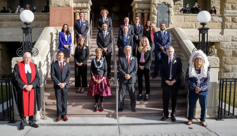 a group of people stand on a staircase outdoors and smile for a photo.