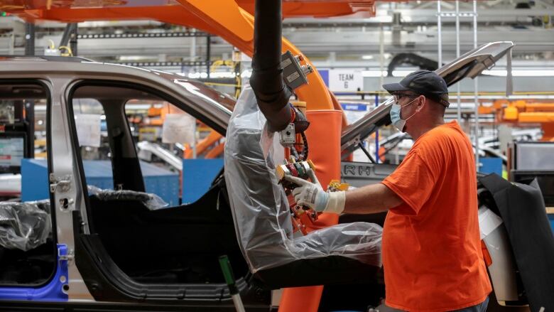 An assembly worker prepares to install seats in a 2021 Jeep Grand Cherokee L frame on the assembly line at the Detroit Assembly Complex in Detroit, Michigan in June 2021. The U.S. economy has been hit hard by a microchip shortage that has slowed down vehicle sales. 