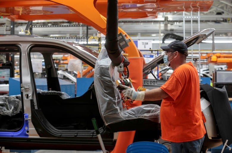 An assembly worker prepares to install seats in a 2021 Jeep Grand Cherokee L frame on the assembly line at the Detroit Assembly Complex in Detroit, Michigan in June 2021. The U.S. economy has been hit hard by a microchip shortage that has slowed down vehicle sales. 