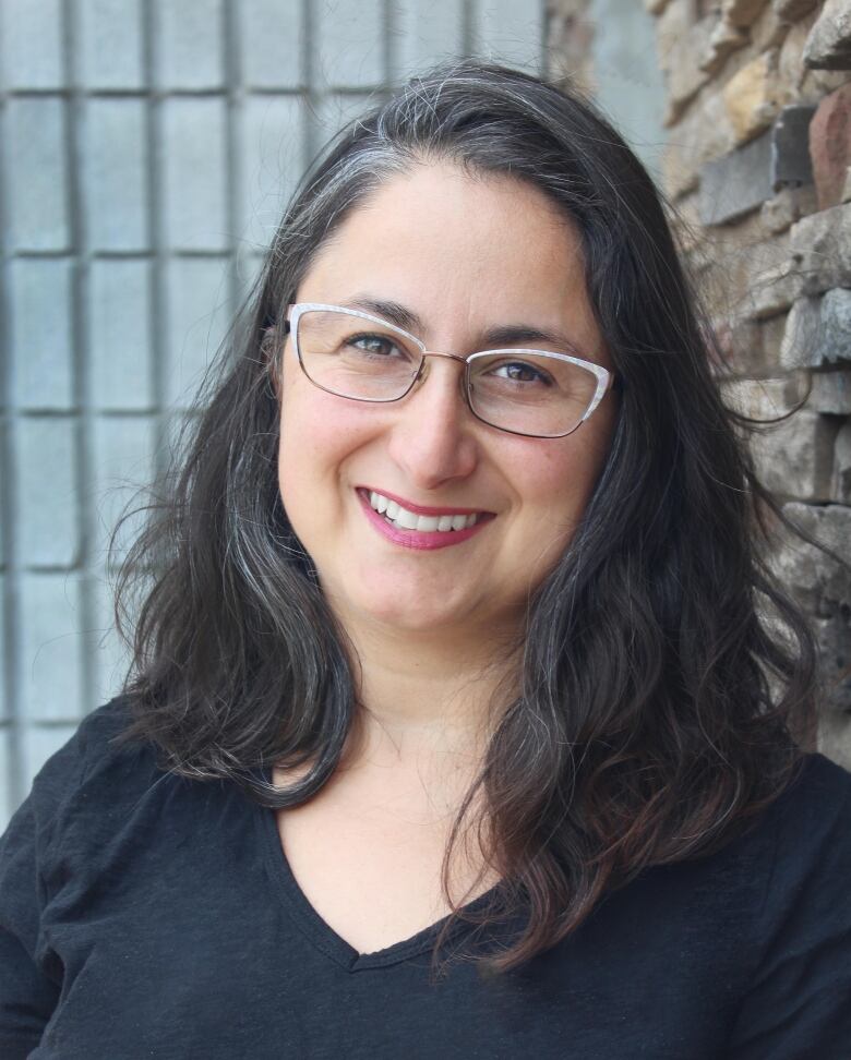 A smiling woman with dark hair, wearing glasses.