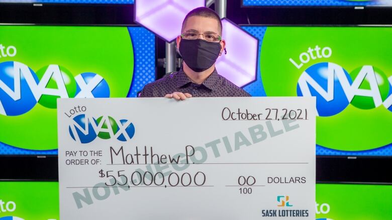 A man holds a large cheque for $55 million.