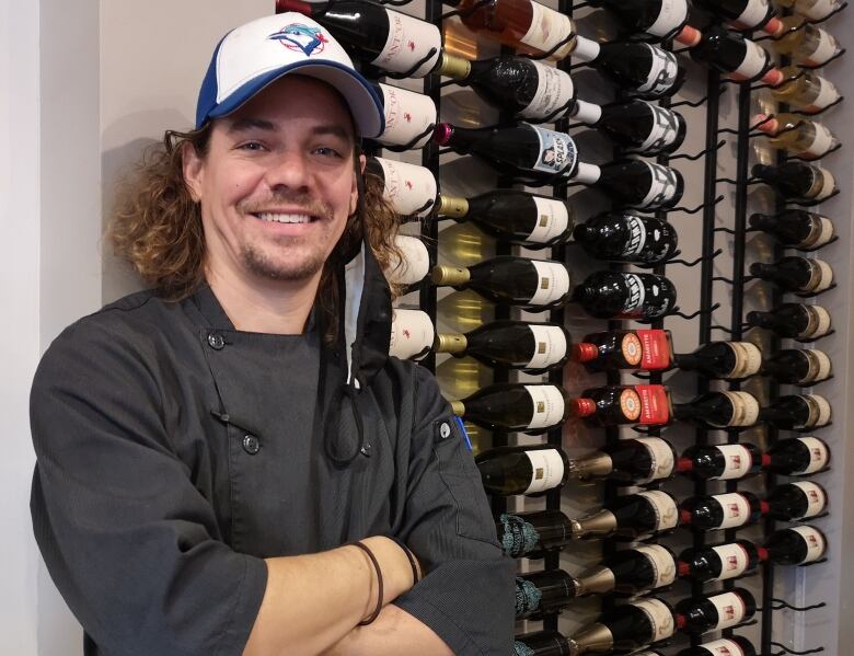 Dan McCowan, chef-owner at Red House in Waterloo stands in front of a rack of wine with his arms crossed.