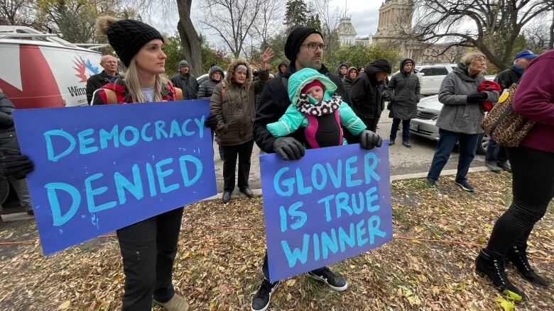 People standing on a lawn, holding signs that read 