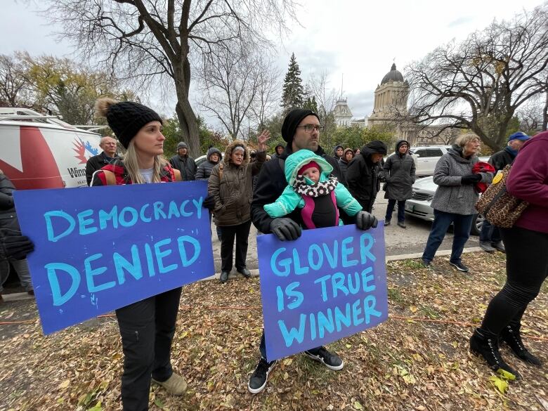 People standing on a lawn, holding signs that read 