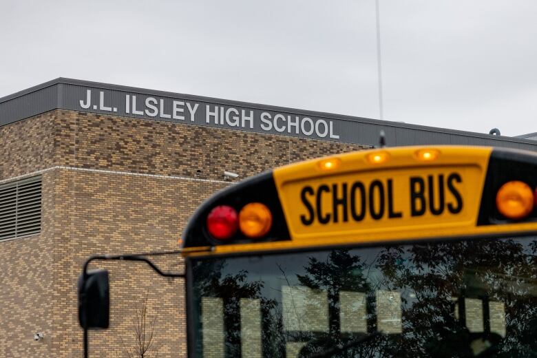 A sign for a high school and a school bus are shown.