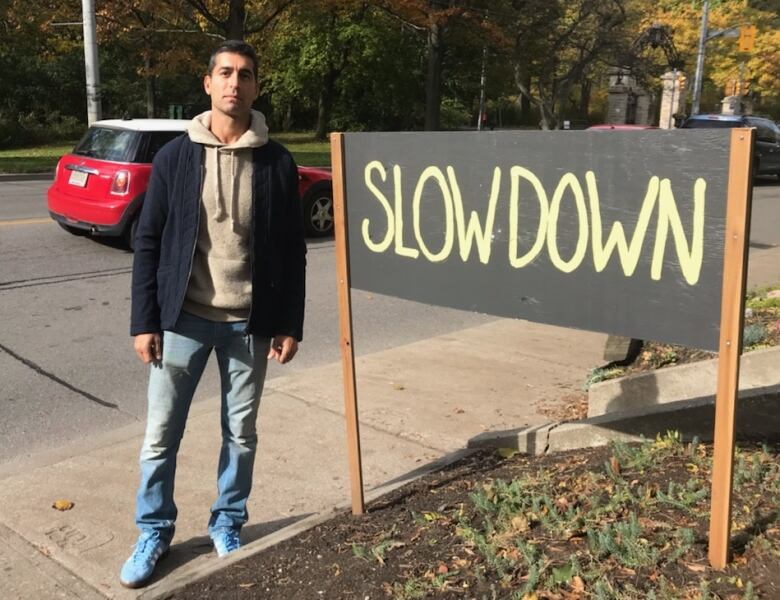 A man stands beside a big sign saying 