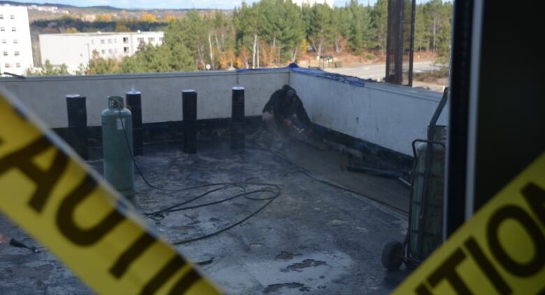 Caution tape frames a construction worker out on a roof