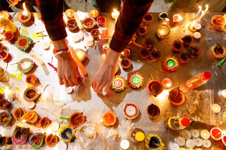 A woman lights candles outside the Hindu Sabha temple, in Brampton, Ont., on Nov. 4, 2021, in observance of the first day of Diwali.