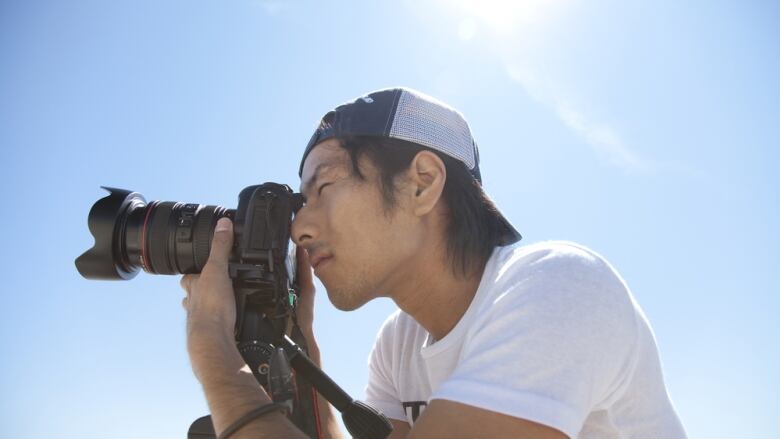 A man with a camera aimed off screen takes a photo.