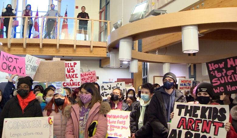 Young people in masks with signs.