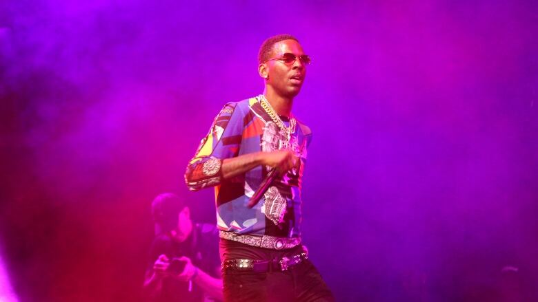 Young Dolph performing in moody purple lighting.