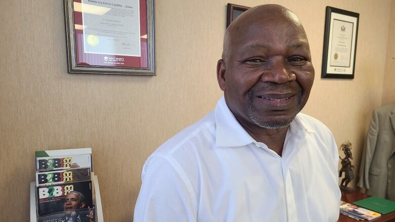 A Black man wearing a white short sleeved button up