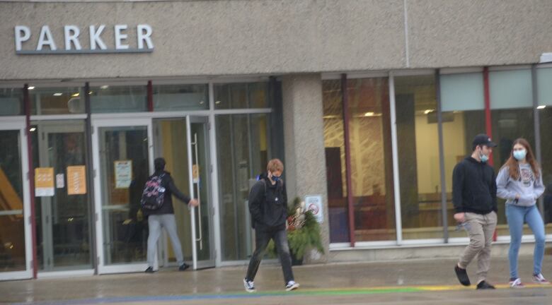 Students walking outside a large university building.