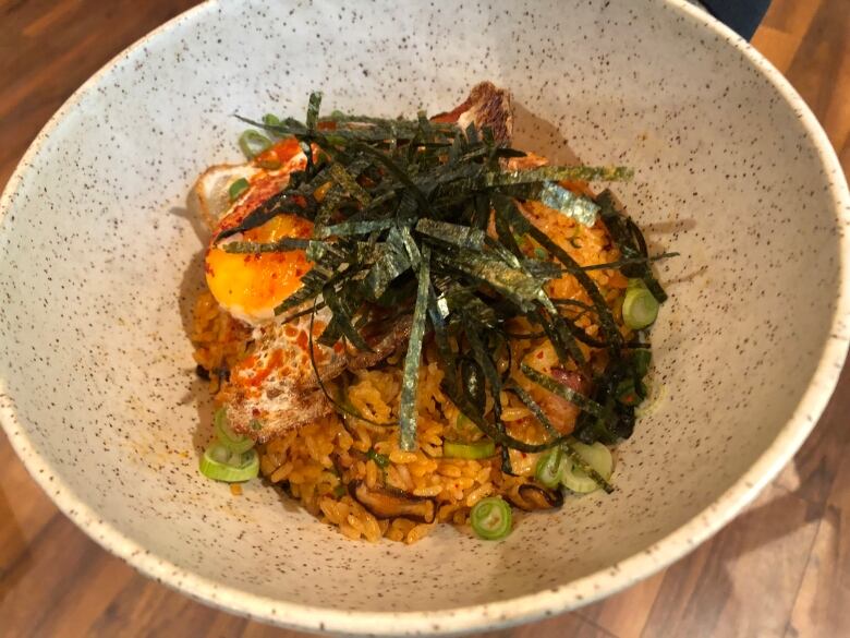 A bowl of rice topped with shredded seaweed.