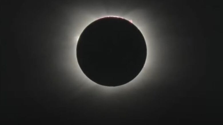 A bright circle almost completely covered by a dark circle.