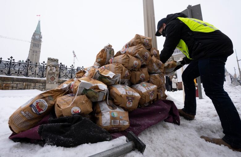 Bags of Prince Edward Island potatoes are unloaded from a transport truck on Dec. 8, 2021 in Ottawa with Parliament Hill in the background. 