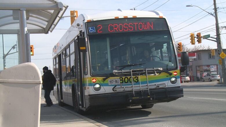 A bus at a bus stop where a passenger is getting off