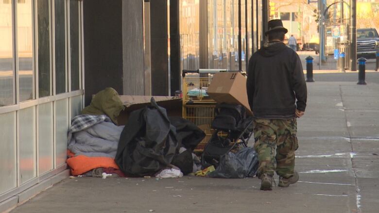 A man walks by a makeshit tent on the street.