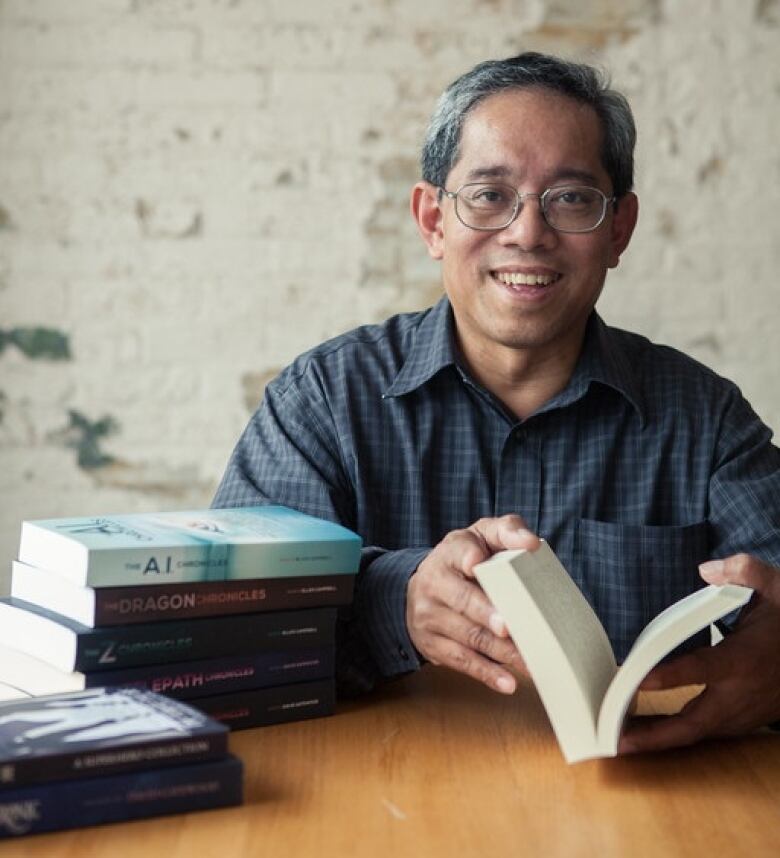 A man holding an open book smiles at the camera in a portrait photo.