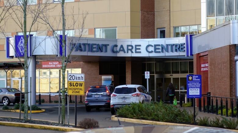 Two cars are stopped in front of the Royal Jubilee Hospital's entrance. Above the cars is a sign that reads, Patient Care Centre. 