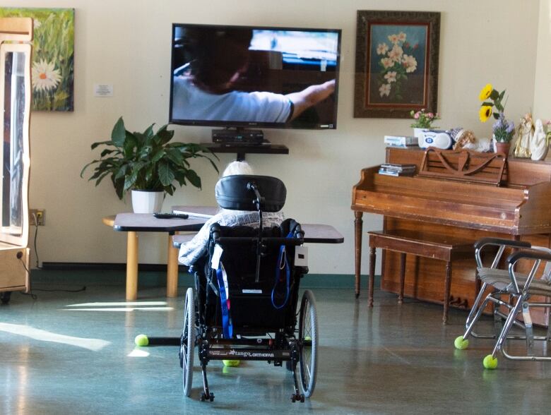 A resident in a wheelchair watches television in a seniors' home.