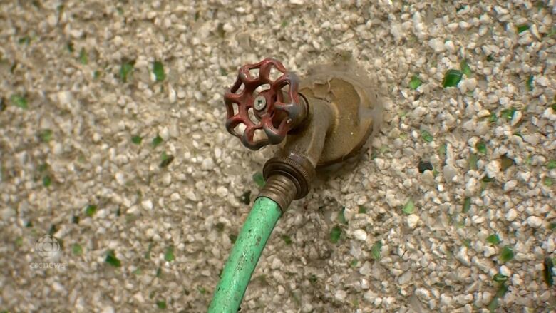 A garden hose is seen attached to a house.