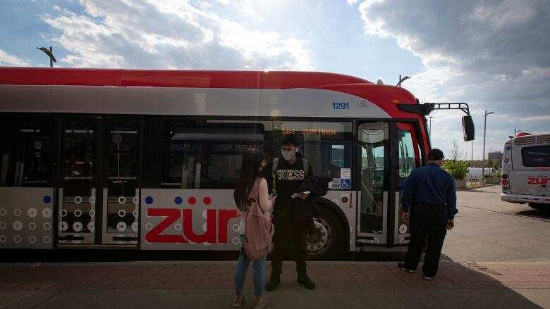 People standing in front of a bus. 