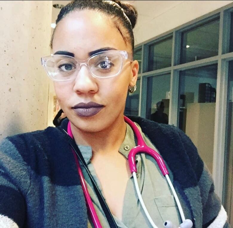 A Black woman wearing glasses and scrubs