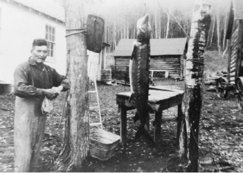 a man with a sturgeon outside his home in the years before the construction of the Kenney dam. 