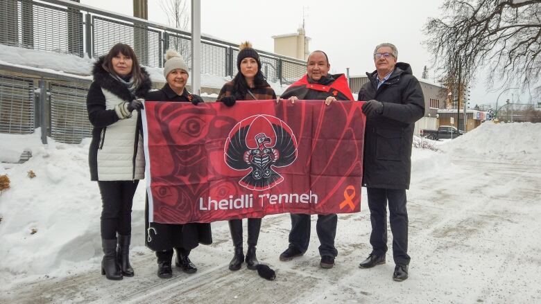 A group of people hold up a flag.