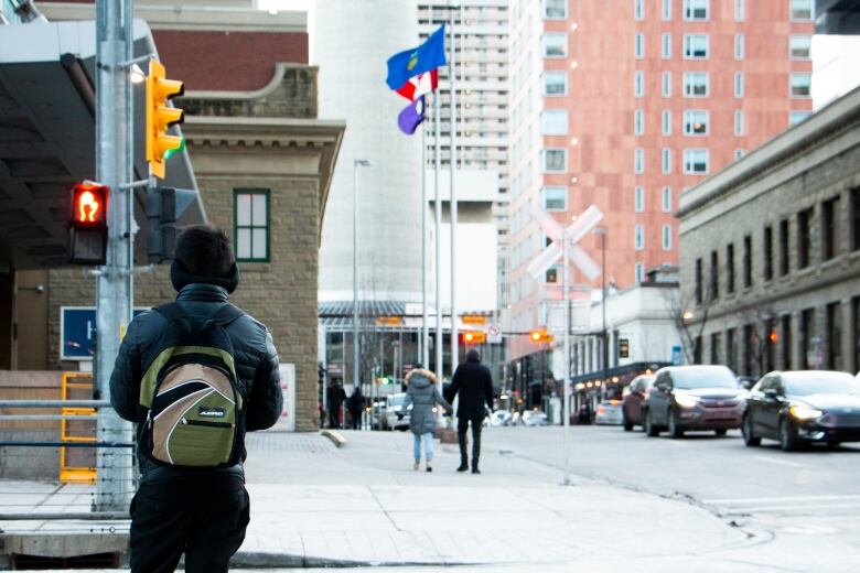 Pedestrian waiting at a crosswalk in downtown Calgary in the winter