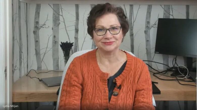 A woman wearing an orange sweater.