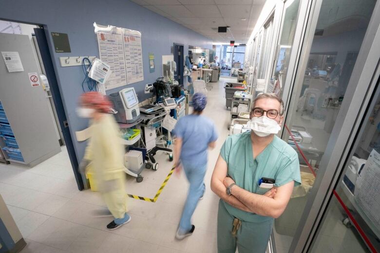 A man stands in a bustling hospital intensive care unit. 