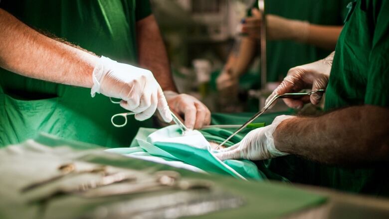 A shot of surgeons holding instruments near a patient.